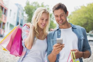 Hip young couple looking at smartphone on shopping trip